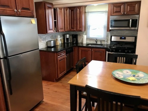 Modern kitchen with wooden cabinets, stainless steel appliances, and a dining table set with a decorative plate.