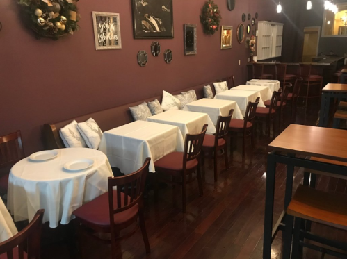 Cozy restaurant interior with tables set for dining, adorned with white tablecloths and decorative wall accents.