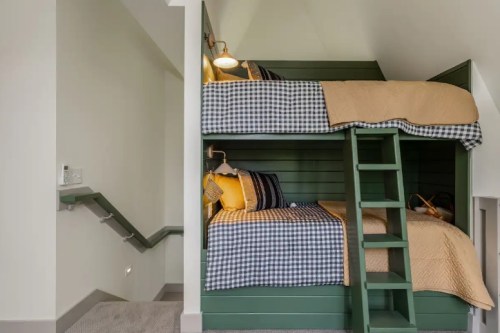 Cozy bunk beds with green walls, checkered bedding, and a ladder, in a well-lit, modern room.