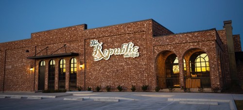 Exterior of The Republic building, featuring brick walls and illuminated signage, at dusk.