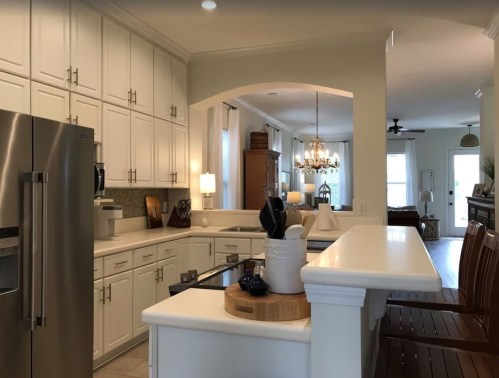 Bright, modern kitchen with white cabinets, stainless steel appliances, and a view into a cozy living area.