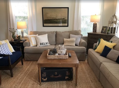 Cozy living room with beige sofas, decorative pillows, a wooden coffee table, and warm lighting.