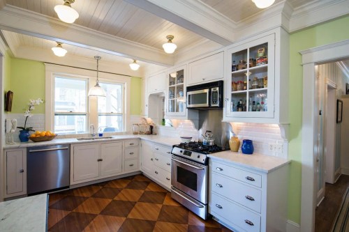 Bright kitchen with white cabinets, a gas stove, and a window, featuring a mix of modern and classic design elements.