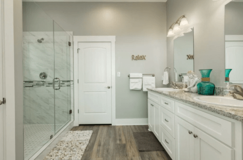 Modern bathroom featuring a glass shower, double vanity, and neutral tones with a "Relax" sign on the wall.