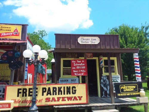 A colorful vintage barber shop with signs for free parking and Western Union, set against a bright blue sky.