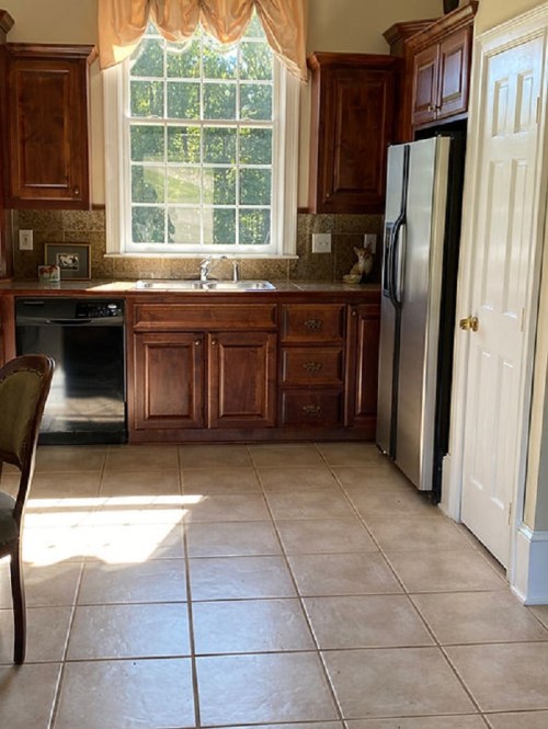 Bright kitchen with wooden cabinets, stainless steel appliances, and a large window letting in natural light.