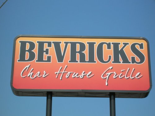 Sign for Bevricks Char House Grille against a clear blue sky.