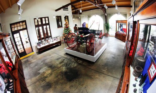 Interior of a museum featuring a vintage carriage, holiday decorations, and display cases with artifacts.