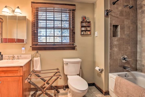Cozy bathroom featuring a wooden vanity, shower, bathtub, and natural light from a window with blinds.