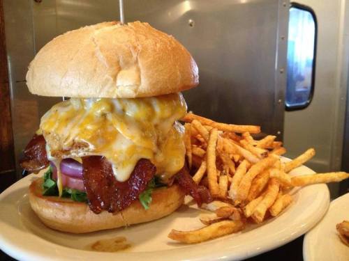 A juicy burger with melted cheese, bacon, lettuce, and tomato, served with a side of crispy fries.