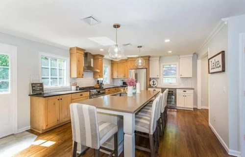 Bright kitchen with wooden cabinets, a large island, and modern appliances, featuring a cozy dining area and natural light.