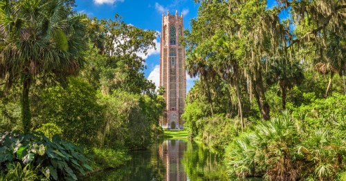 the carillon tower at bok tower gardens in florida surrounded by greenery and by a pond