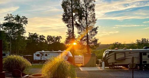Sunset view over an RV park, with trees and campers silhouetted against a colorful sky.