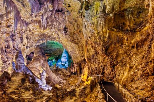 A colorful cave interior with stalactites and stalagmites, featuring a winding path through the rock formations.