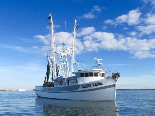 A fishing boat named "Lady Lisa" anchored on calm waters under a blue sky with scattered clouds.