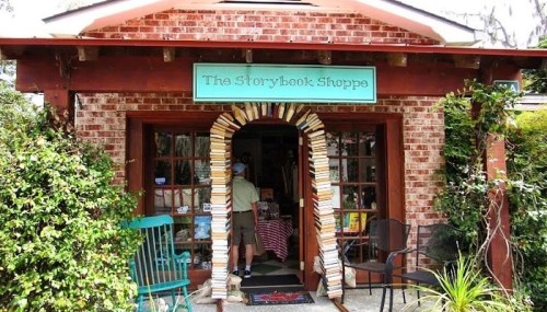 A quaint bookstore entrance with a brick facade, featuring a book arch and a sign reading "The Storybook Shoppe."