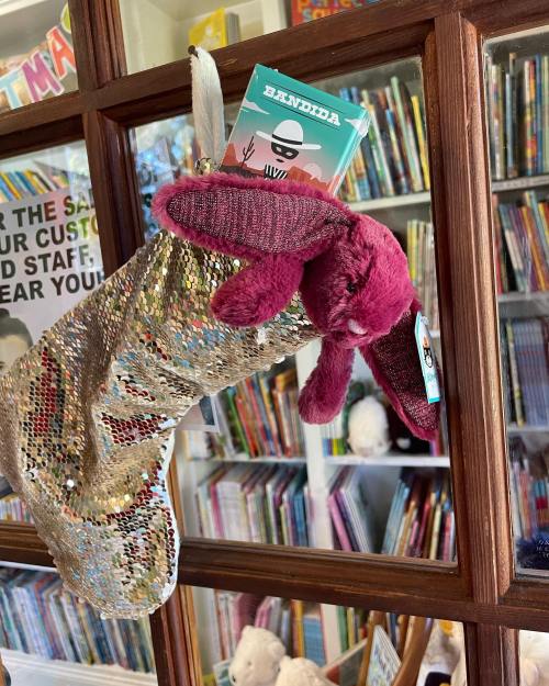 A sparkly stocking hangs from a wooden shelf, holding a card featuring a character named Bandida.