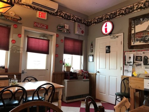 Cozy restaurant interior with red and white decor, tables, and a vintage Coca-Cola sign on the wall.