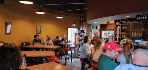 A cozy restaurant interior with patrons seated at wooden tables, chatting and enjoying their meals. Warm lighting enhances the atmosphere.
