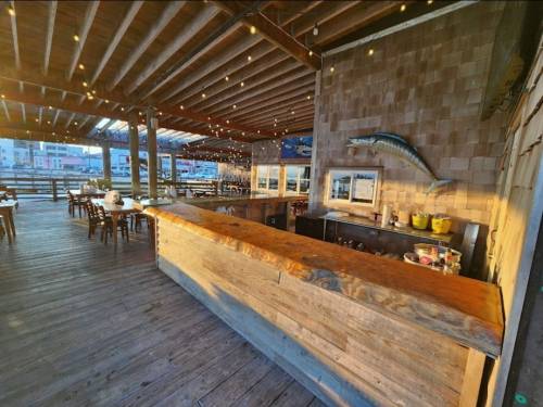 A rustic wooden bar in a spacious, well-lit restaurant with string lights and a fish decoration on the wall.