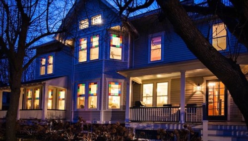 A charming house at dusk, featuring colorful stained glass windows and a welcoming porch.