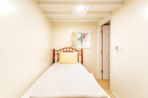 A small, simple bedroom with a single bed, light-colored walls, and a window.