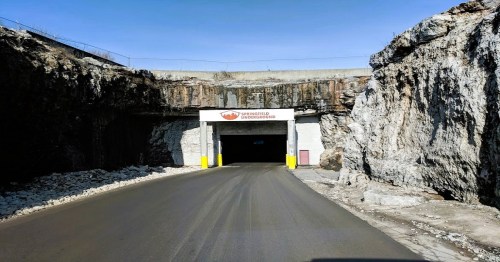 Entrance to a tunnel with rocky walls and a sign reading "Underground." Clear blue sky above.