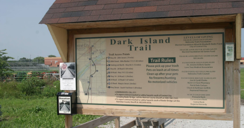 Signboard for Dark Island Trail showing access points, rules, and donation box. Clear instructions for trail users.