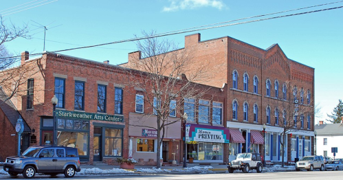 A row of historic brick buildings, including an arts center and a printing shop, on a sunny day.