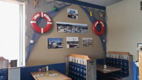 Cozy restaurant interior with blue booths, nautical decor, and photos of boats on the wall. Life preservers hang above.