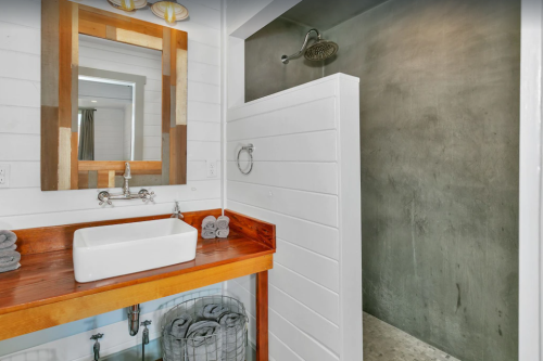 Modern bathroom featuring a wooden vanity, sink, and a sleek shower area with a concrete wall.