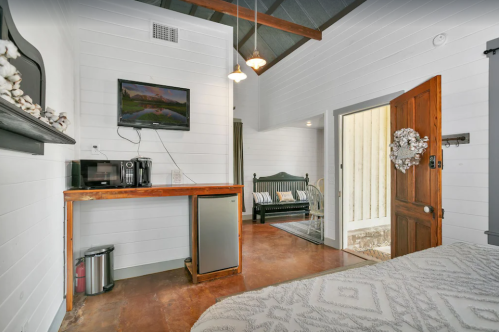 Cozy room with a kitchenette, TV, and a door leading to an outdoor area, featuring rustic decor and warm lighting.