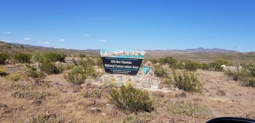 Sign for the Cibola Box Riparian National Conservation Area, surrounded by desert landscape and blue sky.
