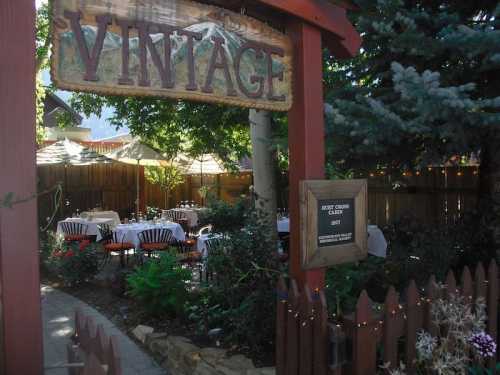 A charming outdoor dining area with tables under umbrellas, framed by a wooden sign reading "Vintage."