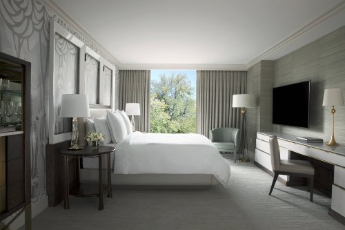 A modern hotel room featuring a king bed, large window with a view, and stylish furnishings.