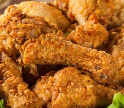 A close-up of crispy, golden-brown fried chicken wings piled on a plate.