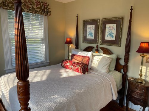 Cozy bedroom with a four-poster bed, decorative pillows, and soft lighting from bedside lamps.
