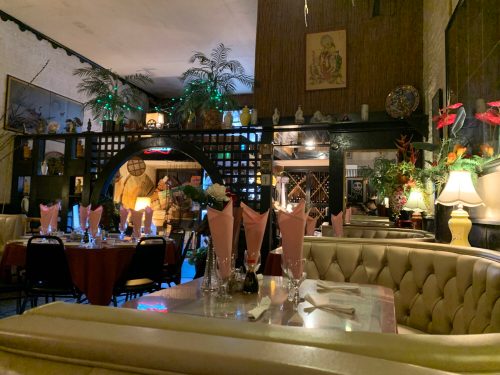 Cozy restaurant interior with pink drinks on tables, soft lighting, and decorative plants creating a warm atmosphere.