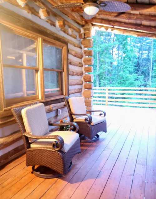 Two comfortable rocking chairs on a wooden porch, surrounded by trees and a serene outdoor setting.