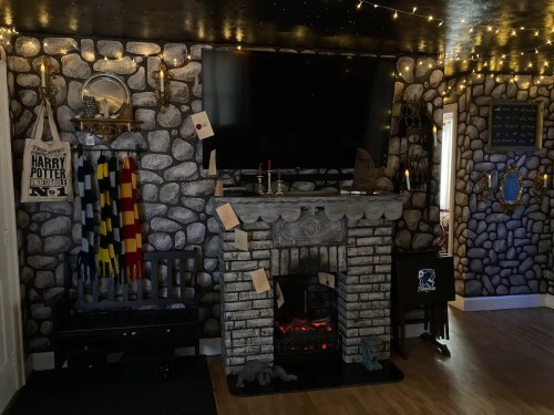 Cozy room with stone wall decor, a fireplace, TV, and Harry Potter-themed items, including scarves and letters.