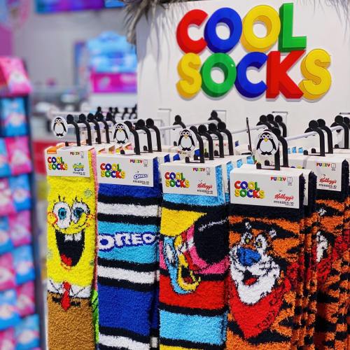 Display of colorful, fun socks featuring cartoon characters, hanging on a rack with a "Cool Socks" sign.