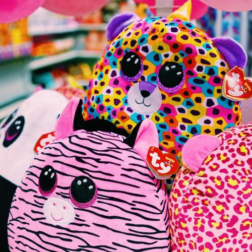 Colorful plush toys with various patterns and cute faces displayed on a shelf in a store.