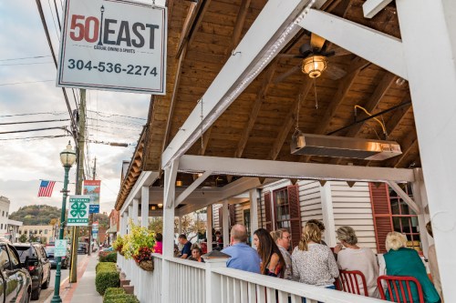 Outdoor dining area of 50 East restaurant, with patrons enjoying their meals under a wooden awning.