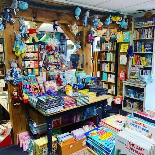 A cozy bookstore filled with colorful children's books and plush toys hanging from the ceiling.