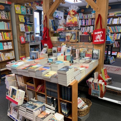 A cozy bookstore display with stacks of books on tables and shelves filled with various titles and colorful book covers.