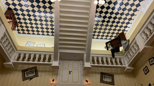 A unique interior view of a staircase with an upside-down ceiling and furniture, creating a surreal atmosphere.