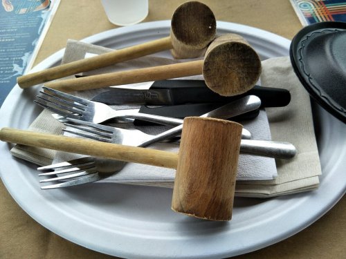 A plate with wooden mallets, forks, and napkins arranged on a table.
