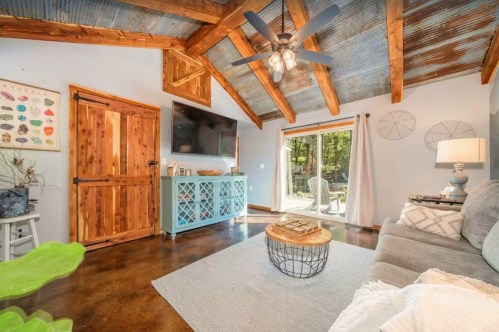 Cozy living room with a rustic ceiling, wooden accents, a TV, and a sliding door leading to an outdoor space.