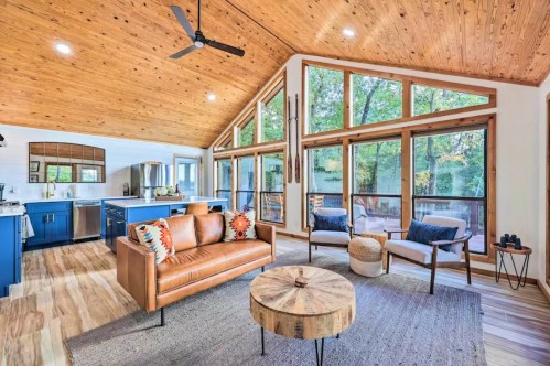 Bright, modern living room with wooden ceiling, large windows, a leather sofa, and a round coffee table.