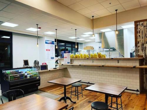 A bright, modern café interior with wooden tables, a drink fridge, and a counter displaying fresh lemons.